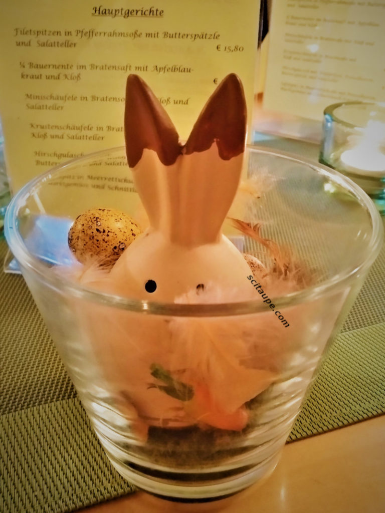 A miniature easter nest with Easter bunny and Easter egg at a dinner table