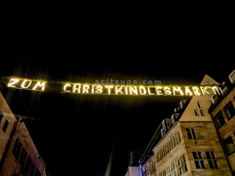 "Zum Christkindlesmarkt" translates to "To the Christkindlesmarkt". This banner is at one of the entries to the market.