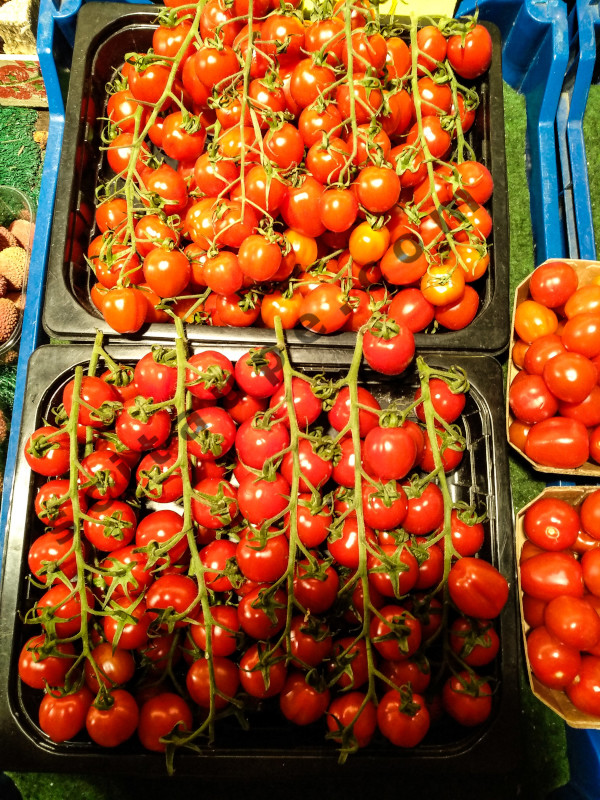 Red tomatoes stacked neatly at a vegetable stall